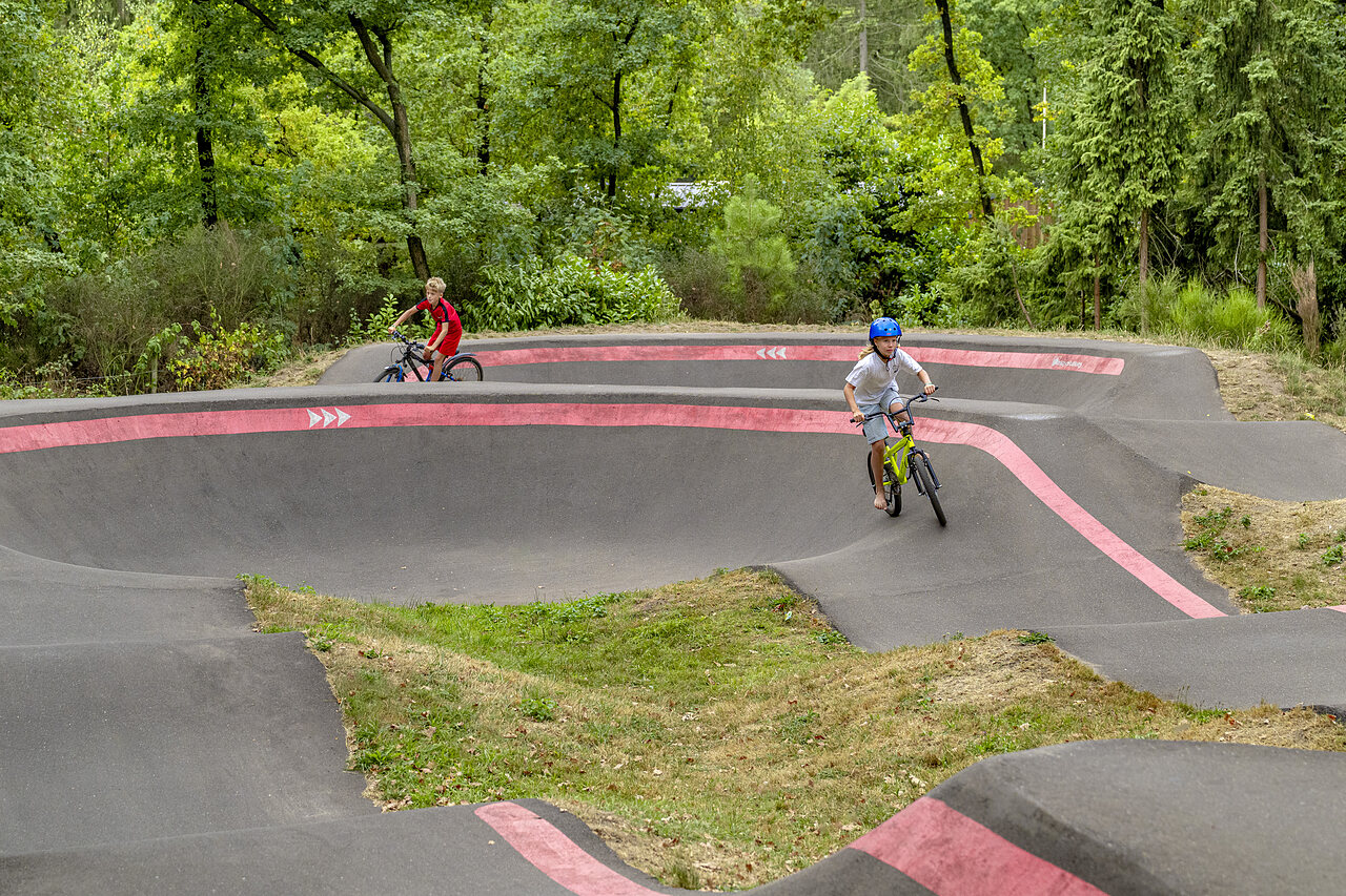Kinderen fietsen op pump track baan op camping CAPFUN Rakelbos, Westelbeers.