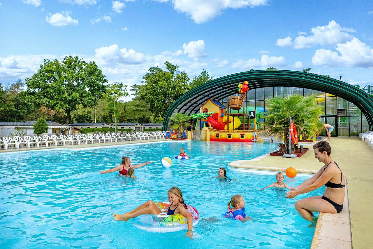Buitenzwembad met waterspeeltuin en gezinnen op camping CAPFUN Rakelbos in Westelbeers.