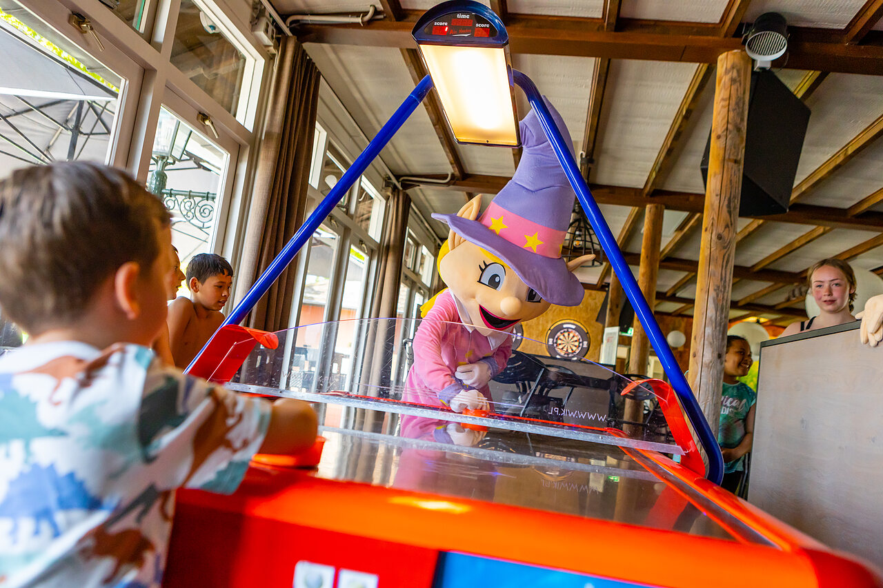 Mascotte en kinderen spelen airhockey op camping CAPFUN Rakelbos in Westelbeers.
