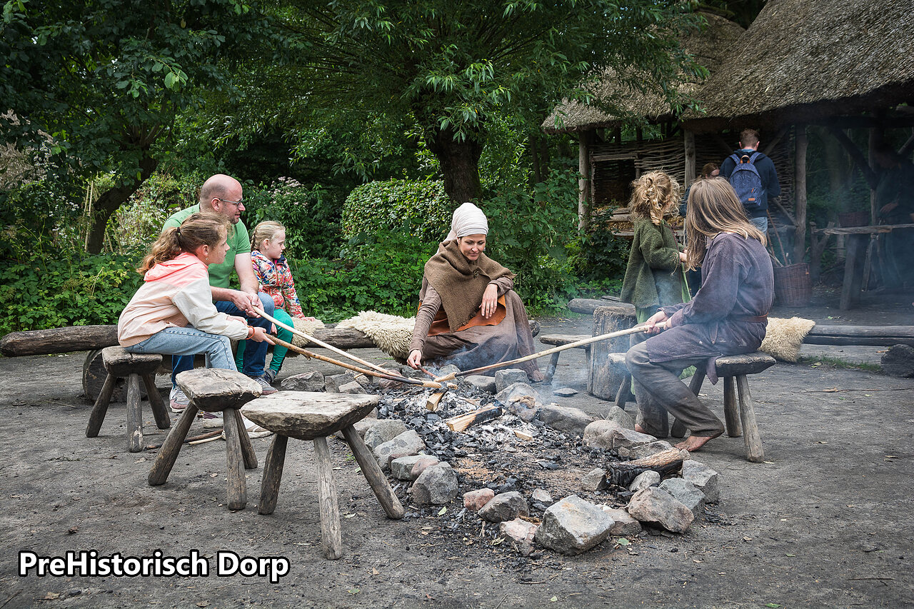 Familie kookt boven vuur in PreHistorisch Dorp Eindhoven, Nederland.