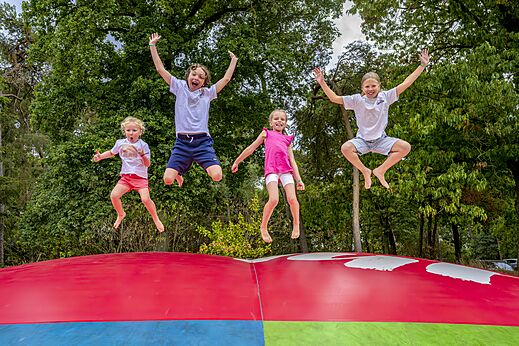 Kinderen springen op een reusachtig springkussen op camping CAPFUN Rakelbos in Westelbeers.