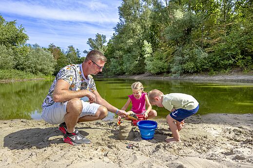 Familie speelt in het zand aan het water op CAPFUN Rakelbos, Westelbeers.