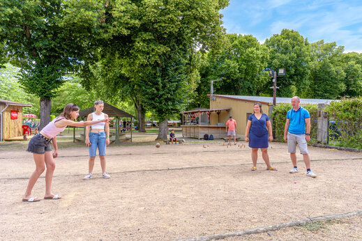 Jongeren en volwassenen spelen jeu de boules op een sportterrein op camping CAPFUN Ranch des Volcans in Chatel-Guyon (63).