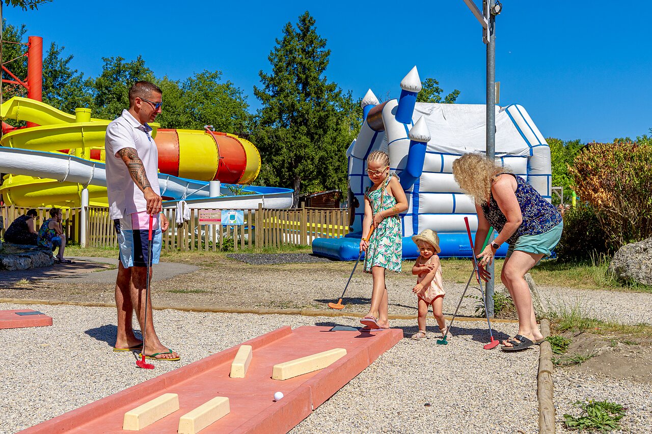 Familie speelt minigolf met waterglijbanen en springkasteel op camping CAPFUN R�gni�re in VILLETTE D'ANTHON (38).