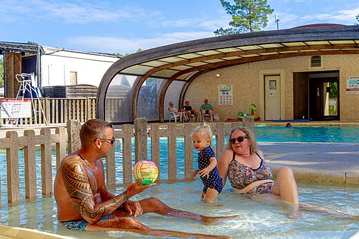 Familie met baby spelend in het overdekte zwembad op camping CAPFUN R�gni�re in VILLETTE D'ANTHON (38).