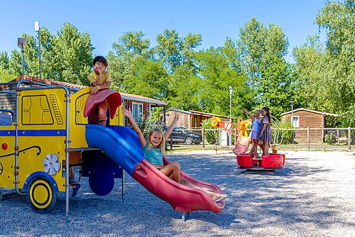 Kleurrijke speeltuin met glijbaan en lachende kinderen op camping CAPFUN Régnière in VILLETTE D'ANTHON (38).