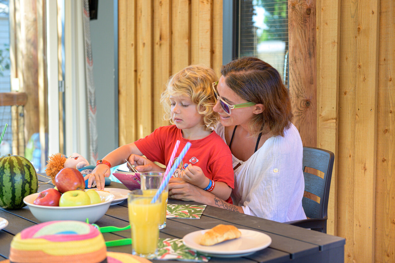 Familie maaltijd op terras stacaravan op camping CAPFUN R�gni�re in Villette d'Anthon.