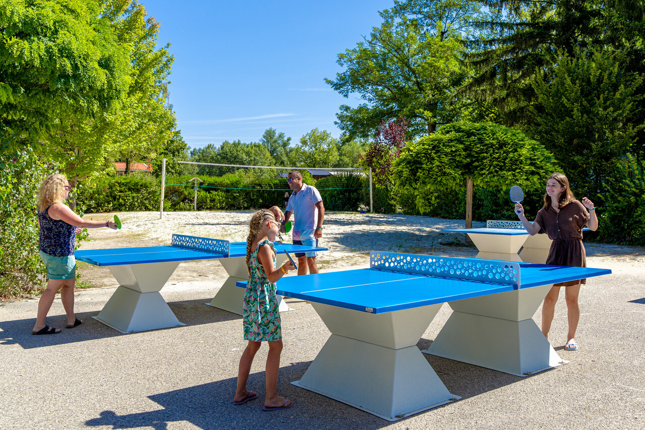 Familie speelt tafeltennis op buitentafels op camping CAPFUN R�gni�re: Boomhutten in Lyon in Villette d'Anthon (38).