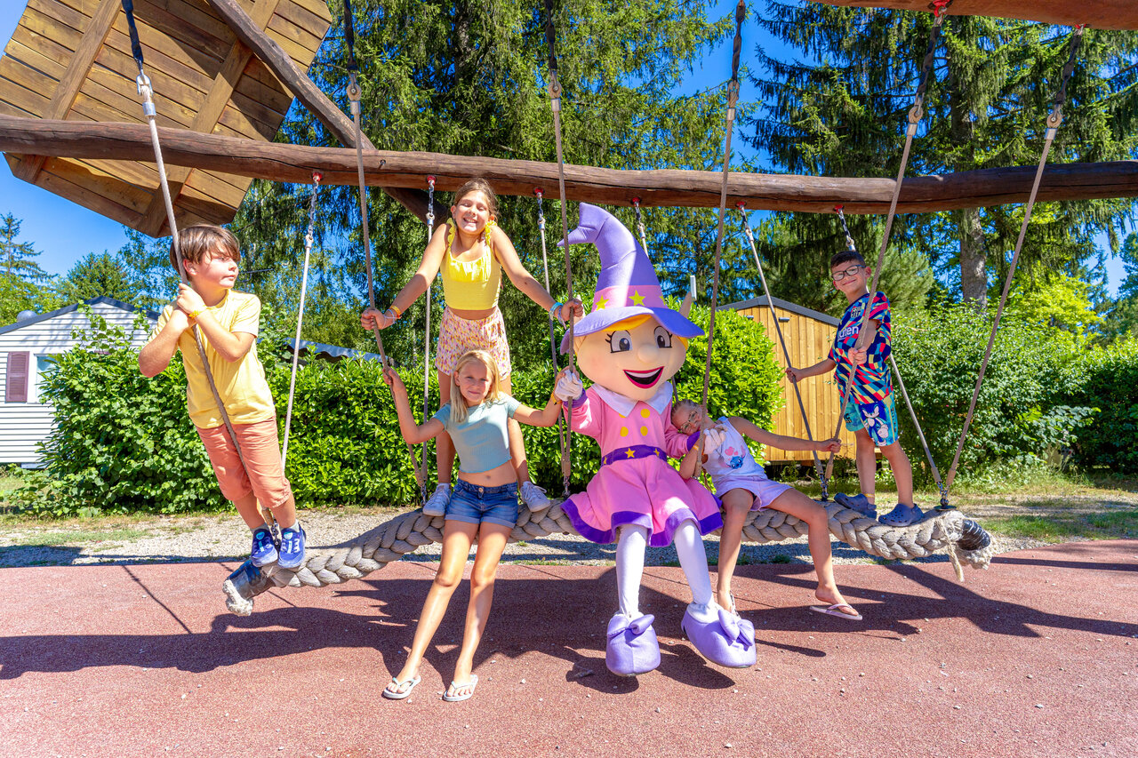 Kinderen en mascotte op reuzenschommel speeltuin op camping CAPFUN R�gni�re in Villette d'Anthon.