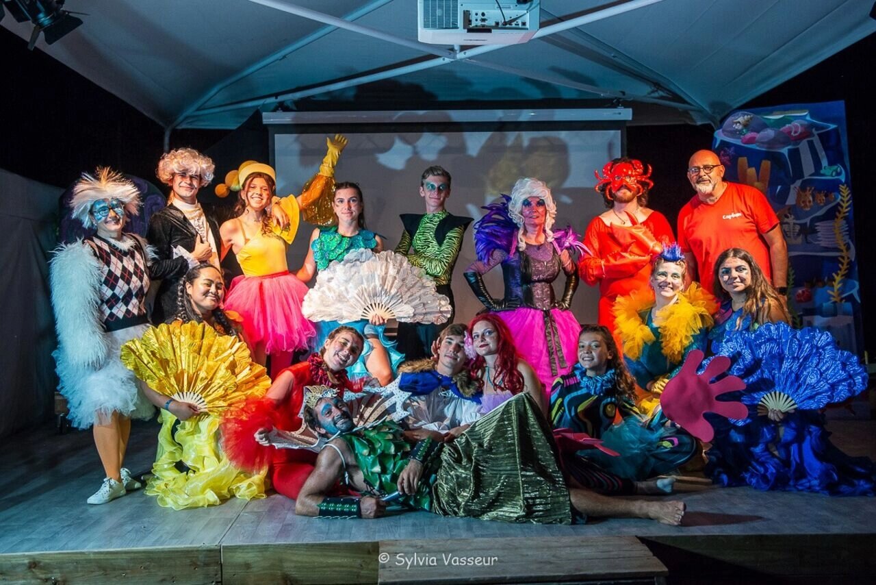 Kleurrijke show met verklede entertainers op podium bij camping CAPFUN La Rivi�re in Valence-en-Poitou.