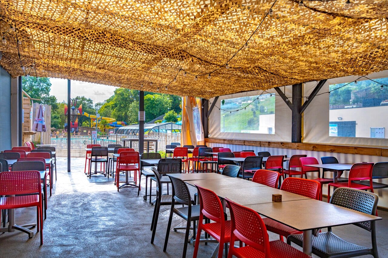 Schaduwrijk restaurantterras, tafels, stoelen, zwembad, op camping CAPFUN La Rivi�re in Valence-en-Poitou (86).