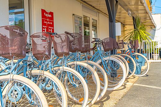 Blauwe huurfietsen met manden op een rij bij camping CAPFUN La Rivière in Valence-en-Poitou (86).