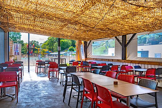 Schaduwrijke buitenrestaurantruimte met tafels en stoelen op camping CAPFUN La Rivière in Valence-en-Poitou (86).