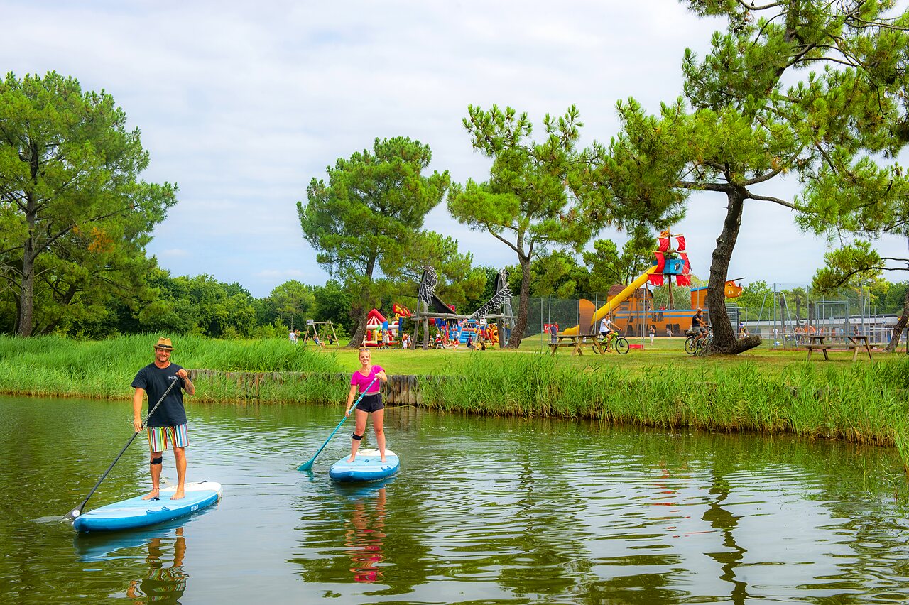 Paddleboarders op water, speeltuin voor kinderen op camping CAPFUN Roumingue in LANTON (33).