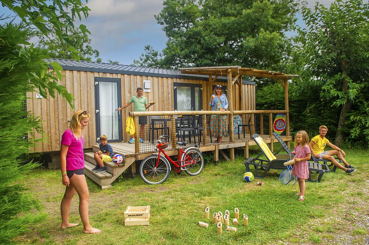 Familie genietend van een moderne stacaravan met terras en spelletjes op camping CAPFUN Roumingue in LANTON (33).