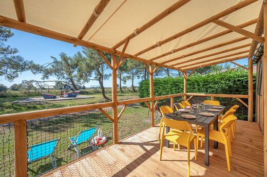Overdekt terras van stacaravan met tafel en gele stoelen bij CAPFUN Roumingue.