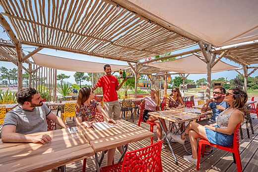Levendig restaurantterras met ober en gasten op camping CAPFUN Roumingue in LANTON (33)