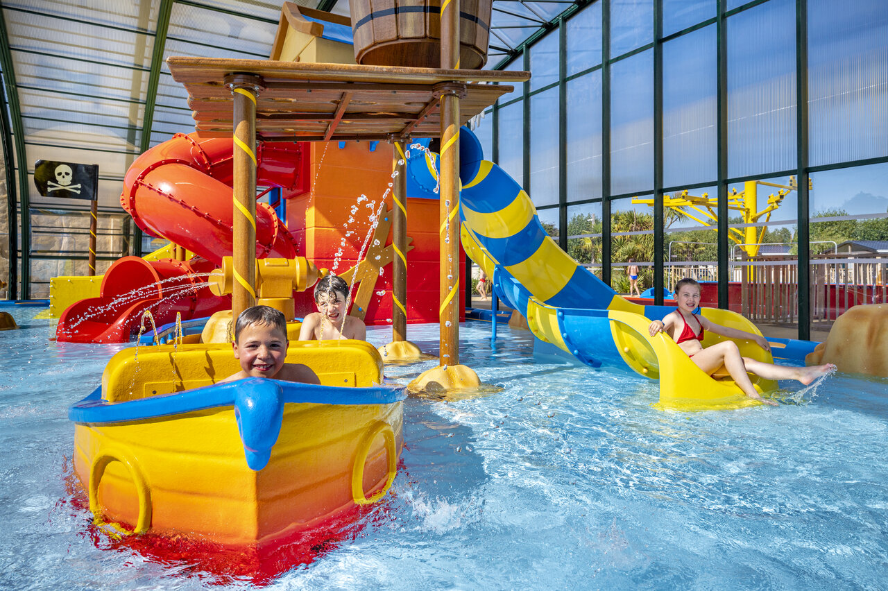 Kinderen spelen in overdekt waterpark met glijbanen op camping CAPFUN La Route Blanche in Breville sur Mer (50).