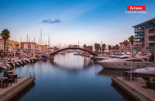 Jachthaven van Fréjus met boten, voetgangersbrug en kleurrijke gebouwen.