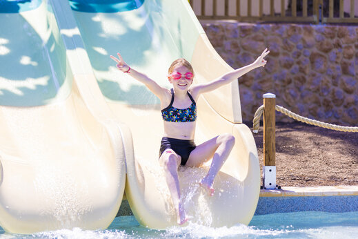 Vrolijk kind op waterglijbaan op camping CAPFUN La Rumba in Fréjus (83).