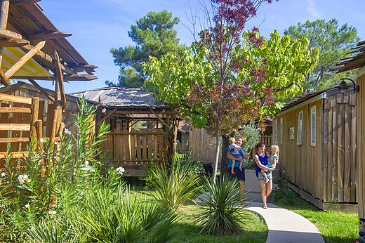 Familie wandelt langs houten accommodaties op camping CAPFUN Sagittaire in VINSOBRES (26).