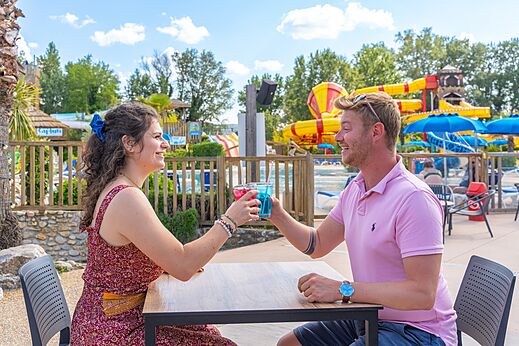 Koppel proostend aan de bar bij waterglijbanen op camping CAPFUN Sagittaire in VINSOBRES (26).
