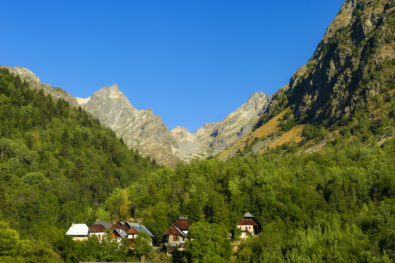 Majestueuze bergen, groen bos en traditionele huizen in de vallei op camping CAPFUN Saint Colomban.