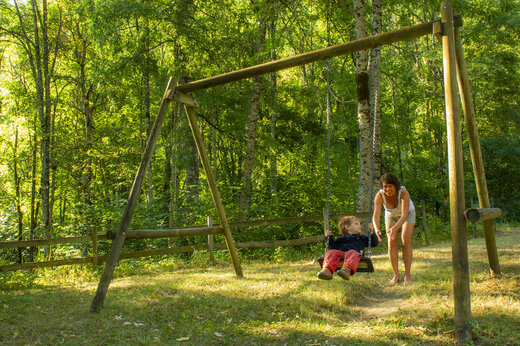 Kind op houten schommel met vrouw op camping CAPFUN Saint Colomban in Saint Colomban des Villards (73).