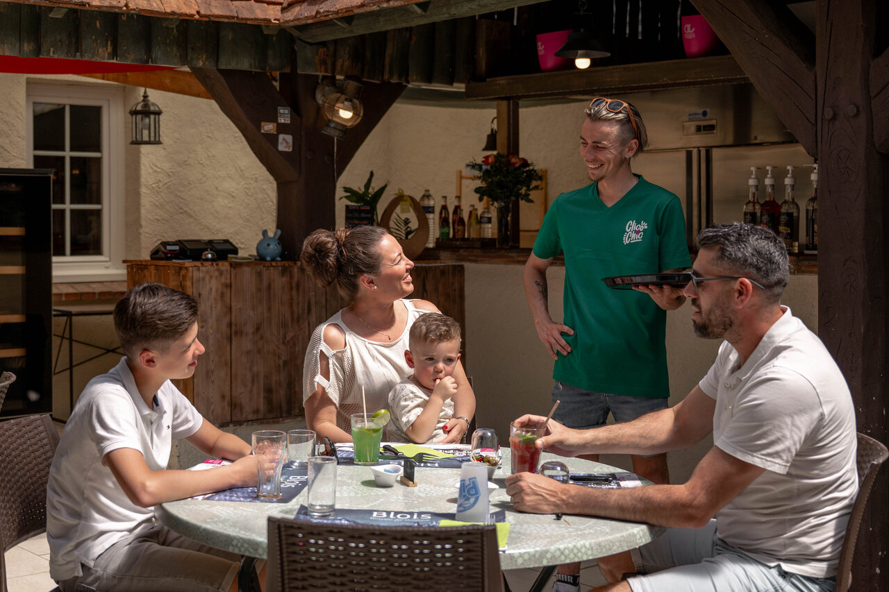 Levendig buitenrestaurant-bar met familie op camping CLICOCHIC Les Saules de Cheverny.