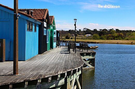 Kleurrijke oesterhutten op palen en terras aan het water, Île d'Oléron.