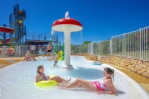 Waterspeeltuin met sproeiende paddenstoel en kinderen op camping VAGUES OCEANES Soleil de Provence in Saint-Romain-en-Viennois (84).