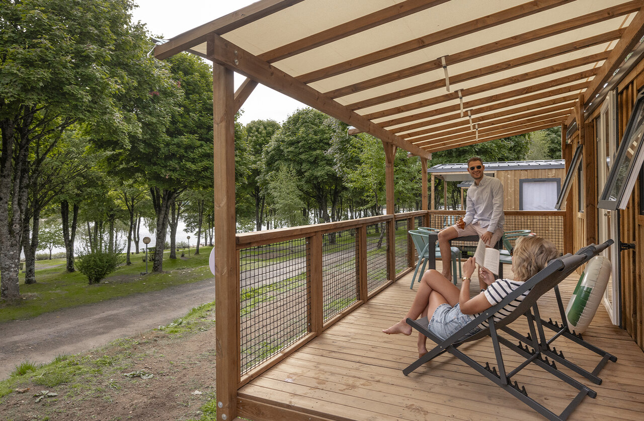Koppel op houten Mobil-home terras, uitzicht meer, op camping CLICOCHIC Soleil Levant.