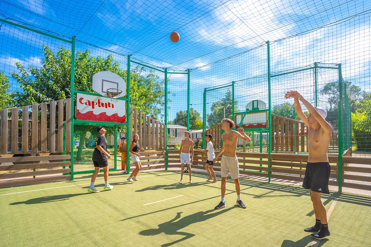 Jongeren basketballen op multisportterrein op camping CAPFUN Soubeyranne in REMOULINS (30).