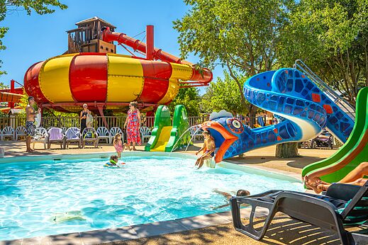 Kleurrijke waterglijbanen en zwembad met spelende kinderen op camping CAPFUN Soubeyranne in REMOULINS (30).