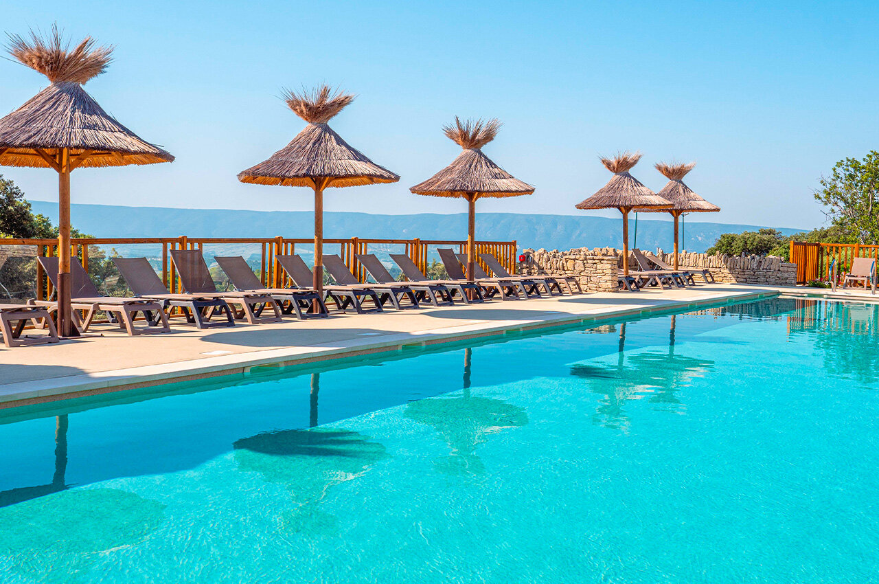 Zwembad, ligstoelen, parasols op camping CLICOCHIC Les Sources de Gordes in GORDES (84).