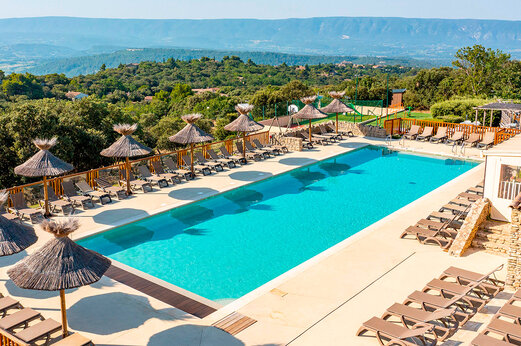 Buitenzwembad met stoelen en parasols op camping CLICOCHIC Les Sources de Gordes in GORDES (84).