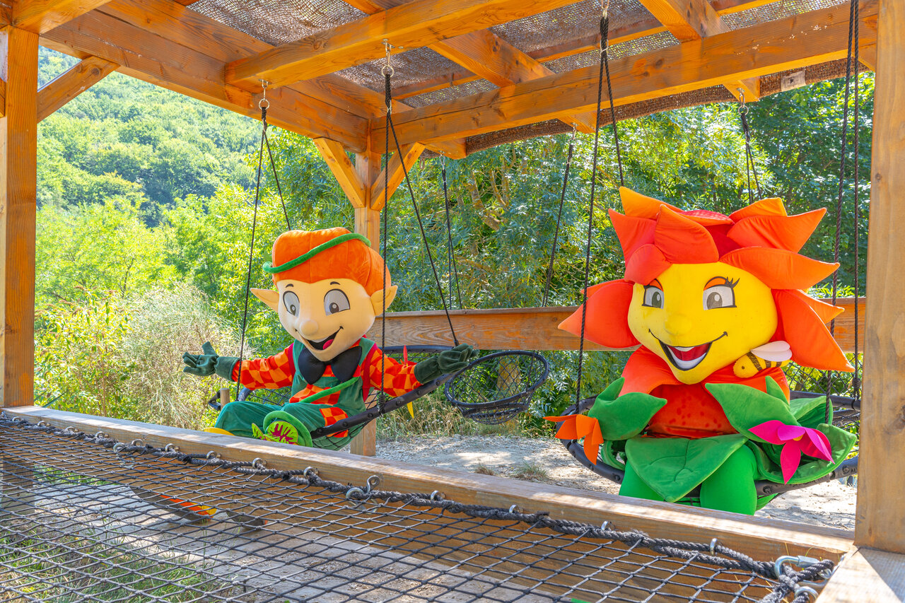 Lachende mascottes op schommels, speeltuin op camping CLICOCHIC Source du Jabron.