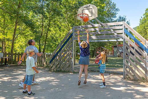 Familie speelt basketbal op het sportterrein van camping CLICOCHIC Source du Jabron.