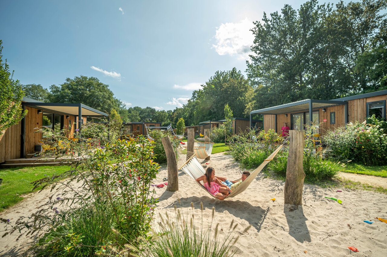 Moderne Mobil-homes met terrassen, kinderen in hangmat op zand bij camping CAPFUN De Sprookjescamping in Rheeze.