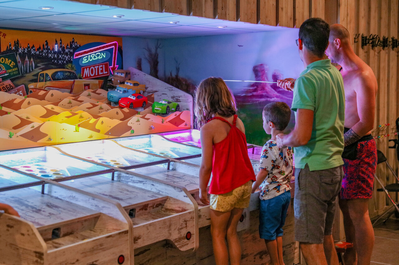 Familie speelt indoor arcadespel op camping CAPFUN De Sprookjescamping in Rheeze.