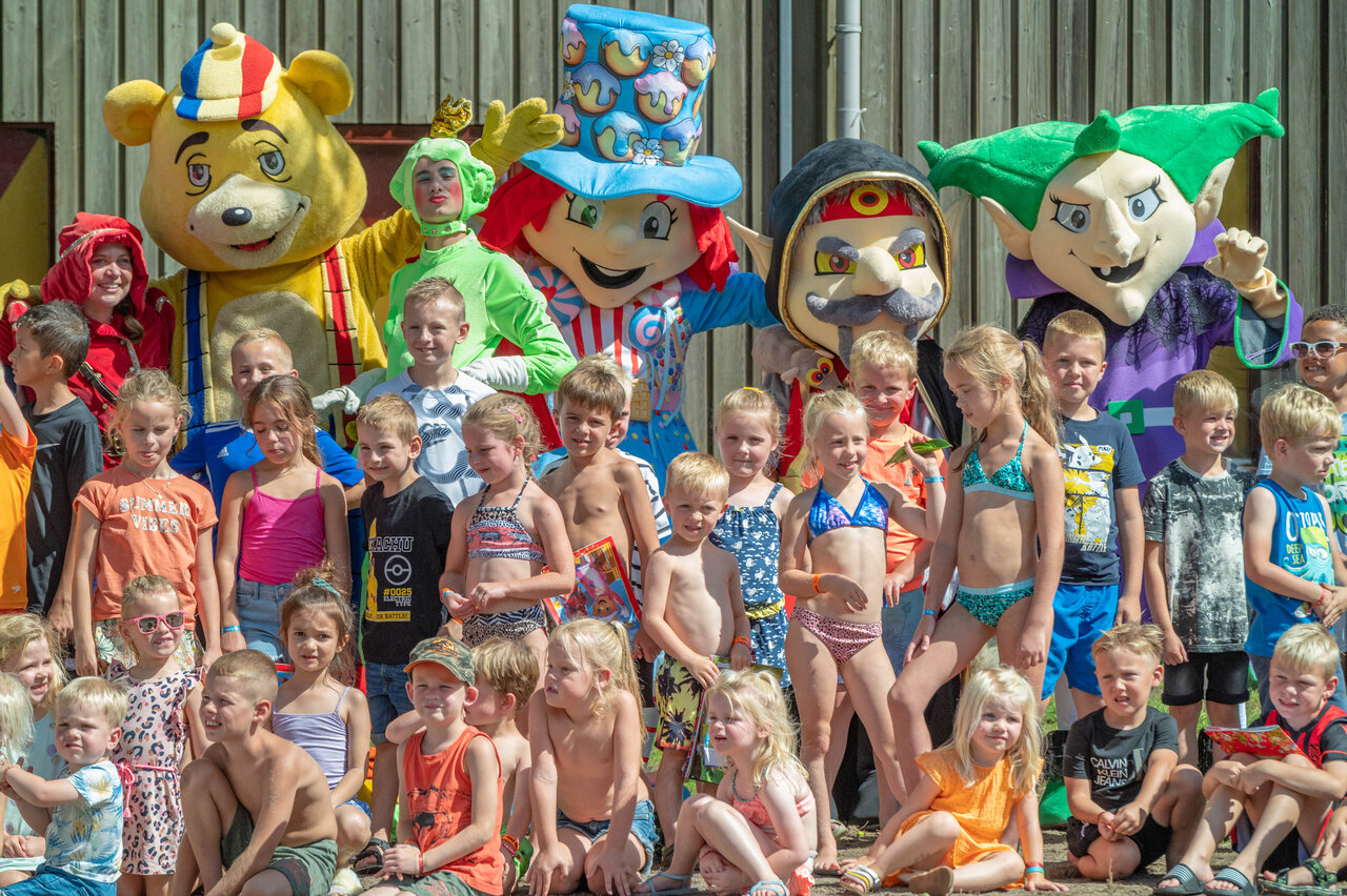 Lachende kinderen met mascottes van animatieteam op camping CAPFUN De Sprookjescamping in Rheeze.