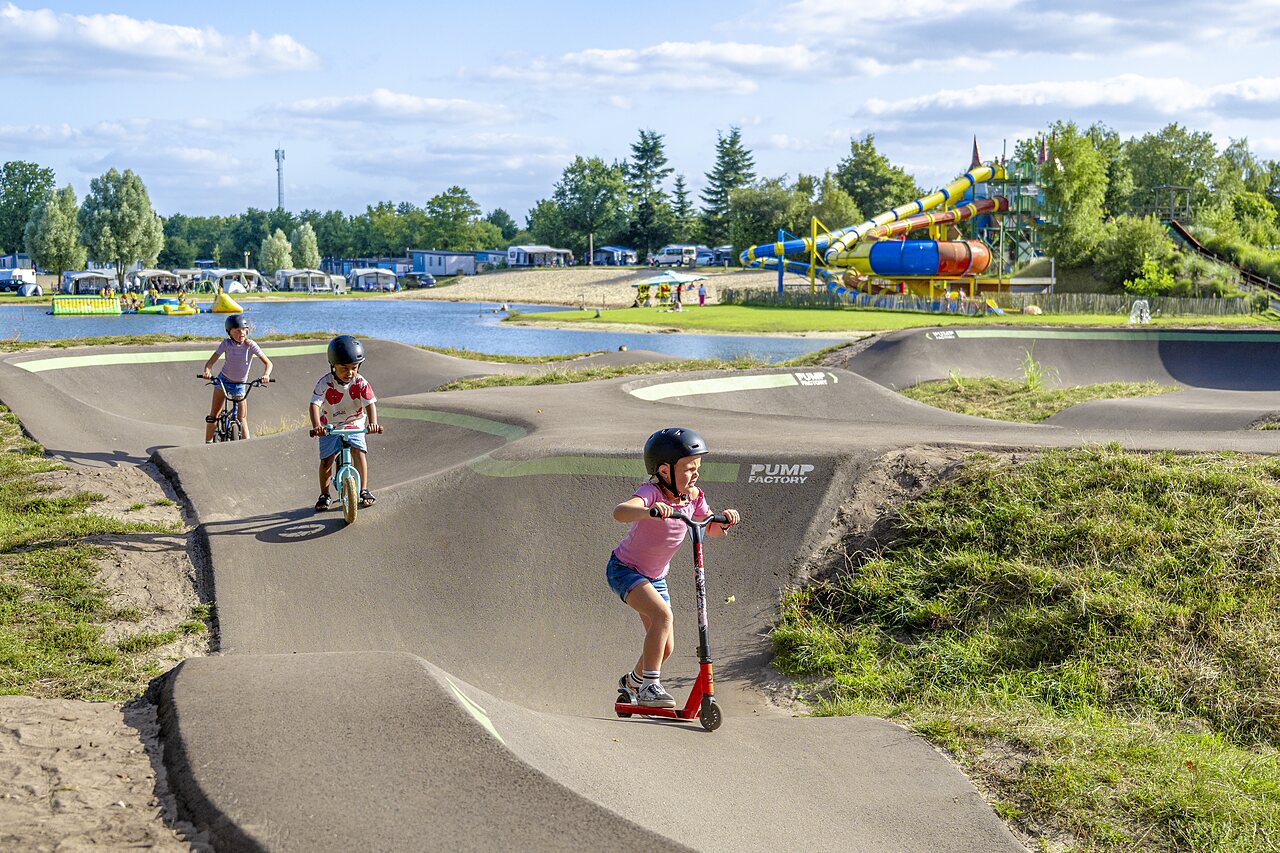 Kinderen op pumptrack met fietsen en step op CAPFUN Vakantiepark het Stoetenslagh.