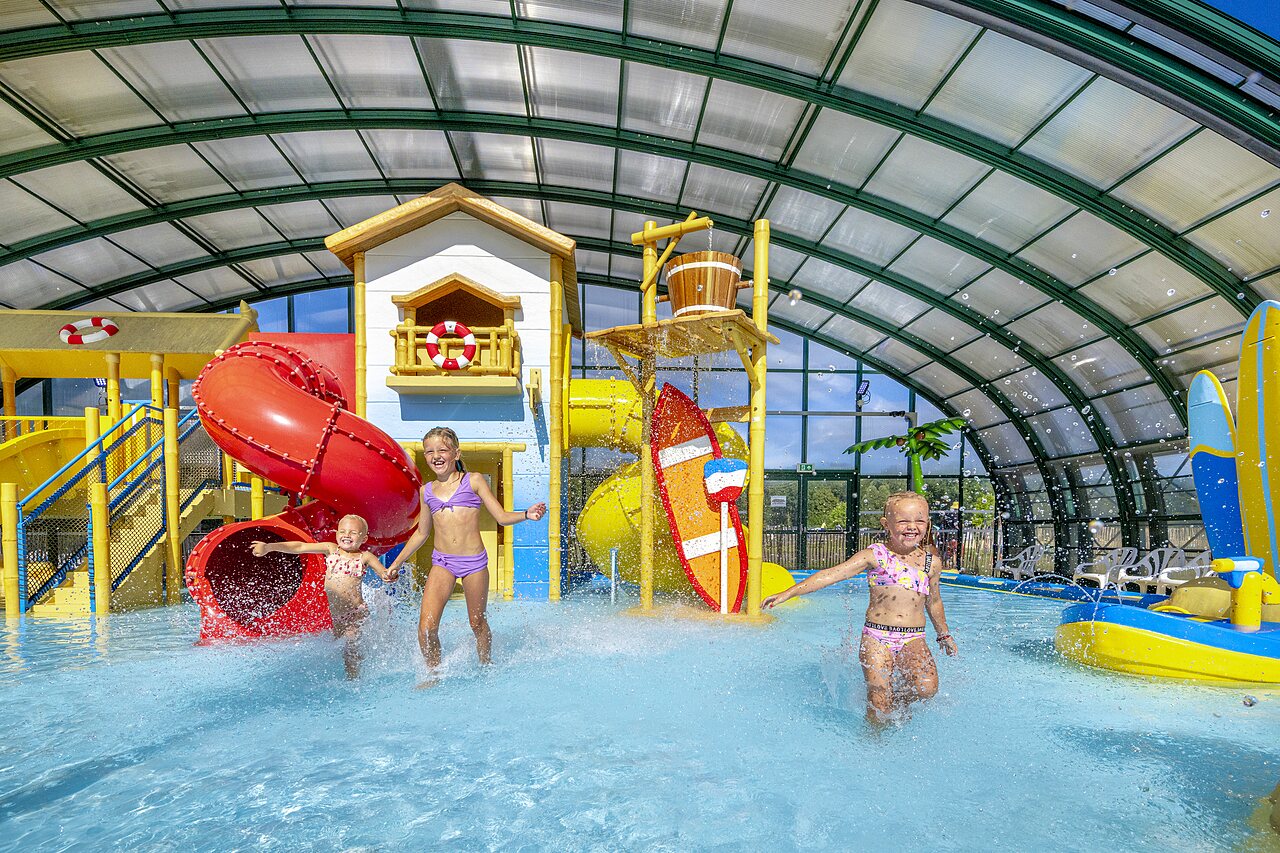 Kinderen spelen in overdekt waterpark met glijbanen op camping CAPFUN Vakantiepark Capfun het Stoetenslagh in Rheezerveen.