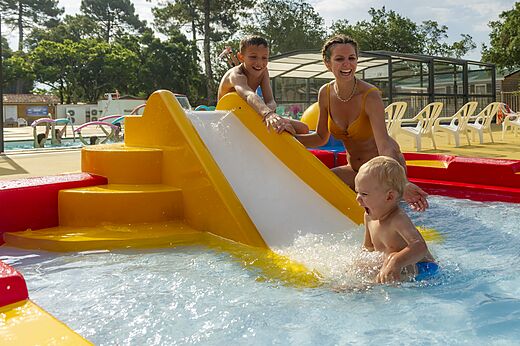 Waterglijbaan en spelende kinderen in het kinderbad op camping CAPFUN Sud Land in Labenne-Ocean (40).