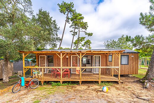 Houten stacaravan met overdekt terras en fiets op camping CAPFUN Sud Land in Labenne-Ocean (40).