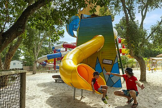 Kind op gele glijbaan zand speeltuin op camping CAPFUN Sud Land in Labenne-Ocean (40).
