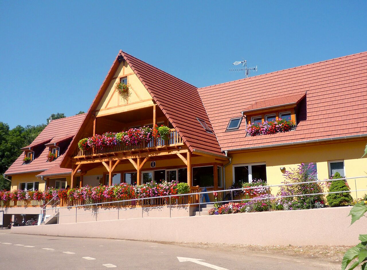 Bloemrijke hoofdreceptie met balkon op camping CAPFUN Suzel in Sainte-Croix-en-Plaine (68).