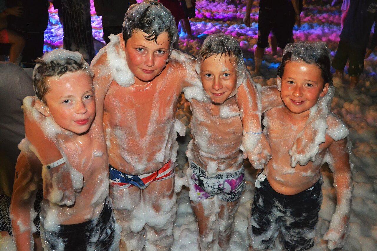 Lachende kinderen genieten van een schuimparty op camping CAPFUN Talaris Vacances in Lacanau (33).