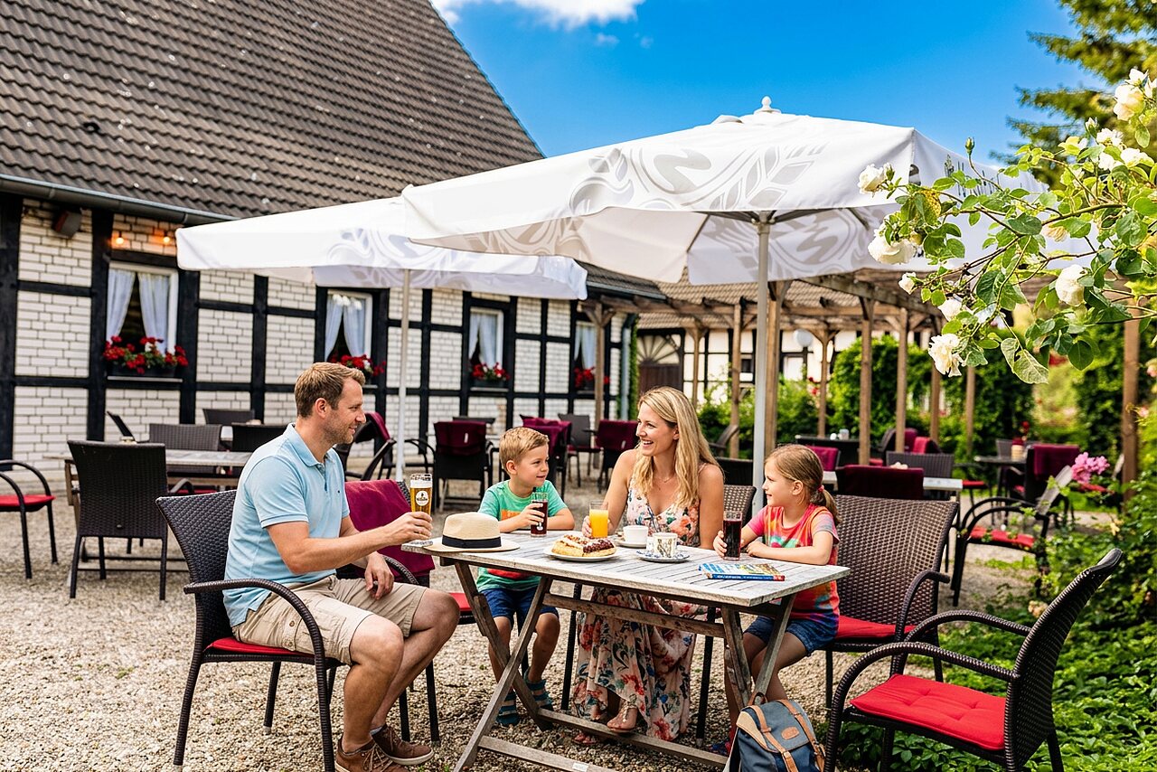 Familie luncht op het buitenterras van het restaurant op camping CAPFUN Tecklenburg in Tecklenburg-Leeden (49).