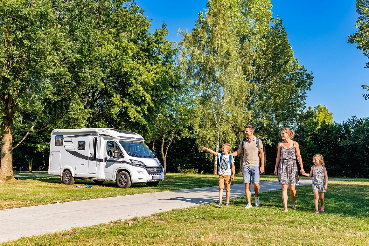 Familie en witte camper op groen terrein op camping CAPFUN Tecklenburg in Tecklenburg-Leeden (49).